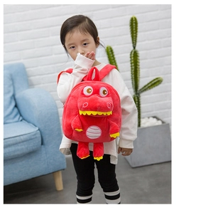 Detail of red plush dinosaur backpack for kids featuring soft fabric and character design