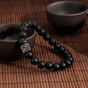 Detailed shot of volcanic stone bead bracelet with a silver letter Z charm on a tea set