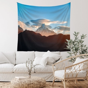 Detail of mountain sunset tapestry hanging above white sofa in cozy living room