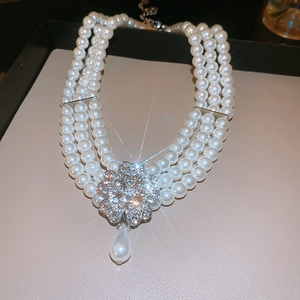 Macro shot of multilayer pearl necklace with crystal flower pendant and teardrop pearl