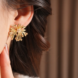 Gros plan de boucles d'oreilles fleurs d'artifice dorées avec zircons sur un mannequin femme