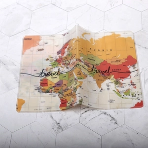 Vista piatta del copri passaporto in PVC con stampa mappa del mondo e scritta travel