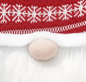 Macro shot of red knitted Christmas gnome hat with white snowflake and plush white beard