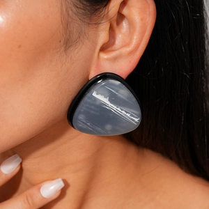 Close-up of oversized geometric resin earrings in dark grey on female model