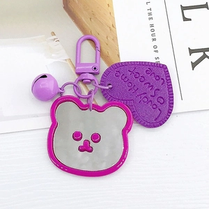 Detail of purple bear mirror keychain featuring a metal heart tag and small bell accessory