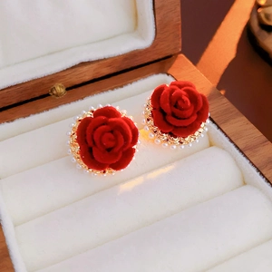 Gros plan sur des boucles d'oreilles fleurs en velours rouge avec perles et base dorée