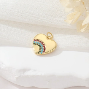 Close-up of golden heart pendant with colorful zircon stones on white fabric