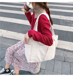 Vue détaillée du grand sac cabas en toile blanc cassé avec plusieurs poches dans la rue