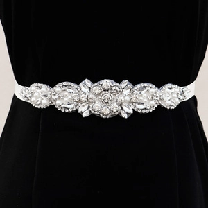 Macro shot of bridal sash featuring marquise rhinestones and pearls on white ribbon