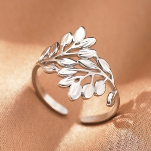 Macro detail of silver leaf-shaped stainless steel ring on brown satin background