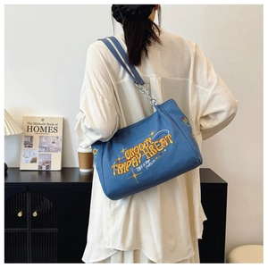Detail of blue canvas tote with colorful embroidery and metal chain shoulder strap