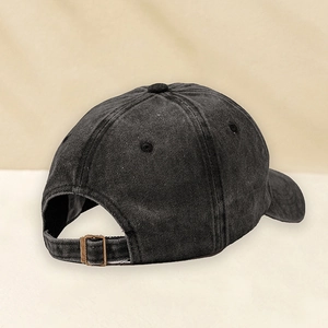 Detail of adjustable vintage metal buckle and washed fabric texture on the black baseball cap