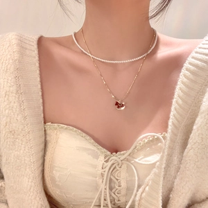 Close-up of double-layer gold plated necklace with pearls and a red horse pendant