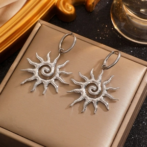 Detailed macro view of silver hollow sun-shaped earrings with textured finish and ear hoops