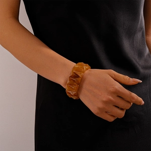 Close-up of amber acrylic geometric bangle with triangular facets worn on wrist
