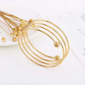 Macro shot of gold multi-layer spiral bangle with sphere ends on minimalist setup