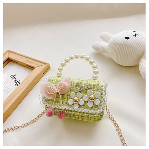 Macro detail of green tweed kids bag featuring pearl handle and lace trim