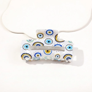 Detailed view of large white hair claw clip with blue evil eye patterns and glossy finish
