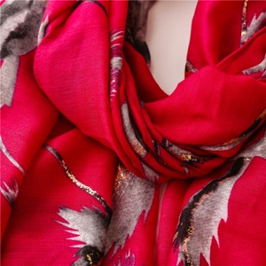 Detail of red scarf showing gold foil accents and delicate feather patterns on soft fabric