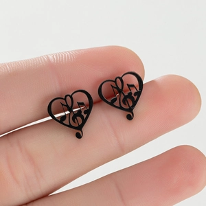 Detail of black heart-shaped music note earrings in stainless steel on hand