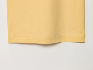 Vue macro du pantalon en sergé jaune vif montrant les coutures précises à double aiguille