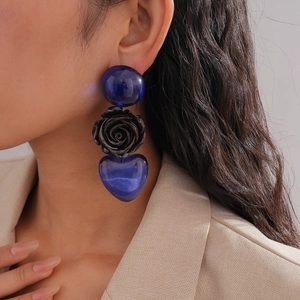Détail de boucles d'oreilles avec perles bleu marine, rose noire et pendentif cœur