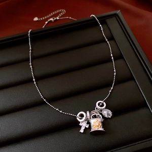Detail view of silver cross necklace with yellow enamel and zircon drop on black leather