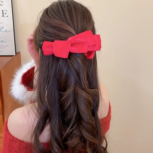 Vue macro d'une grande pince à cheveux nœud rouge multicouche sur cheveux ondulés
