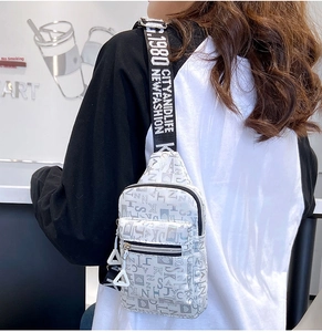 Silver chest bag with letter print and wide jacquard strap shown on a model