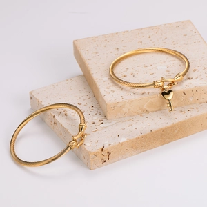 Goldene gedrehte Edelstahldraht-Armbänder mit Herz-Schlüssel-Anhänger auf Steindekor