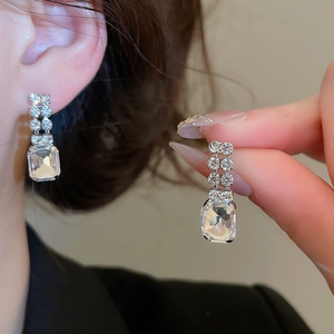Detailed macro view of silver long drop earrings featuring square cut crystal pendants