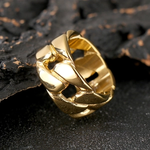 Macro detail of golden Cuban link chain ring on textured black rock background
