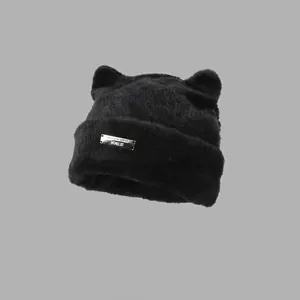 Close-up of black fuzzy cat ear beanie with a metallic plaque and soft plush texture