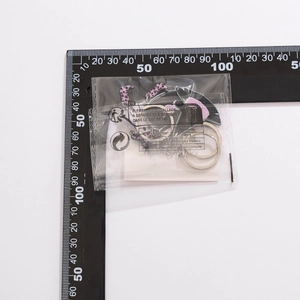 Detail of sweet pink strawberry keychain with black bow charms in clear packaging