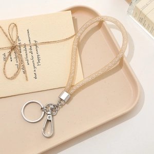 Detail showing a sparkly gold silicone key ring with silver clasp on a beige tray
