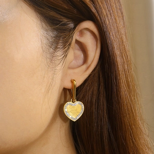 Detailed close-up of golden heart earrings with rhinestones and Love You engraving
