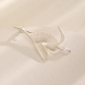 Détail d'une broche kangourou dorée mate avec perle goutte d'eau sur socle en pierre