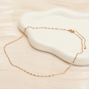 Detail of rose gold stainless steel lip chain on a white ceramic tray with satin background