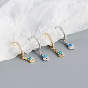 Detailed close-up of opal hoop earrings in gold and silver with blue stones and zircons