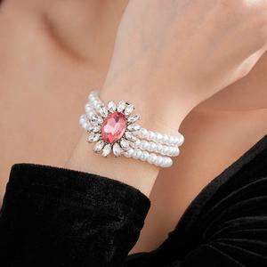 Gros plan d'un bracelet de perles à trois rangs avec gemme rose et fleur de strass