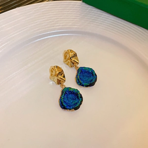 Detail of vintage irregular gold earrings with textured blue-green stone pendants