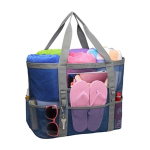 Détail du grand sac de plage en maille bleue avec poches extérieures contenant des serviettes