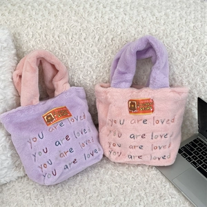 Détail de cabas en peluche avec broderie 'you are loved' et texture douce en fausse fourrure