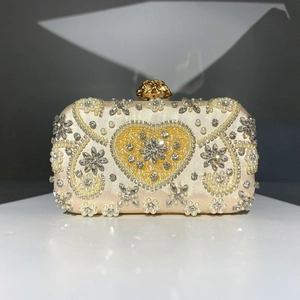 Close-up of handmade beaded evening clutch with pearl heart pattern and floral clasp