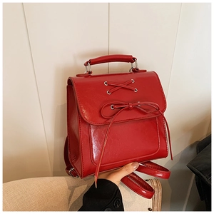 Close-up of bright red retro PU leather backpack with cross strap and bow detail
