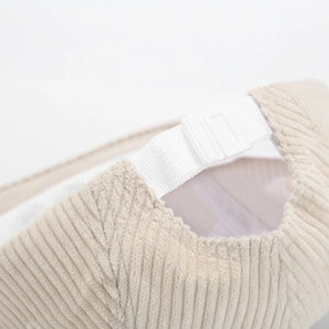 Detail of adjustable strap and plastic buckle on beige corduroy five-panel baseball cap
