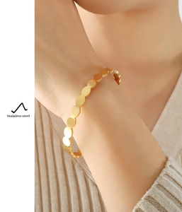 Detailed view of a gold-toned stainless steel bracelet with linked circular disk elements