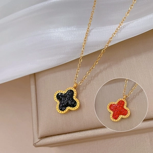 Detail of four-leaf clover pendant in gold with black and red gemstone inlays