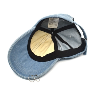 Detail view of denim baseball cap interior showing 100% cotton label and metal rings