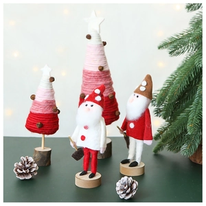 Detail of wool felt Santa gnome figures and pink yarn Christmas tree with wooden bases
